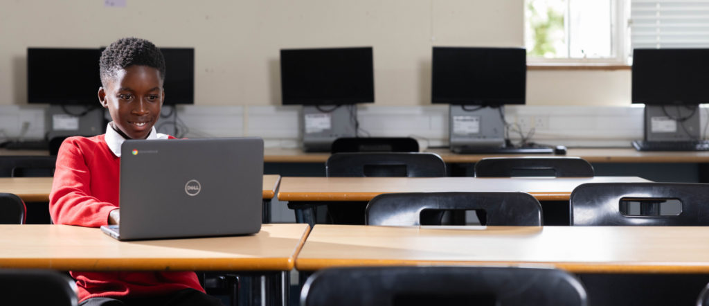 Image shows young school child using a laptop.